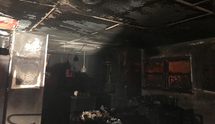 Fire-damaged house with charred walls and soot damaged ceiling
