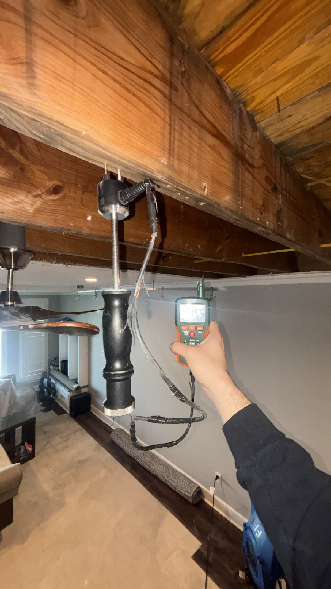 Moisture meter showing readings of 15.5% moisture content in a water-damaged ceiling, indicating ongoing drying efforts.