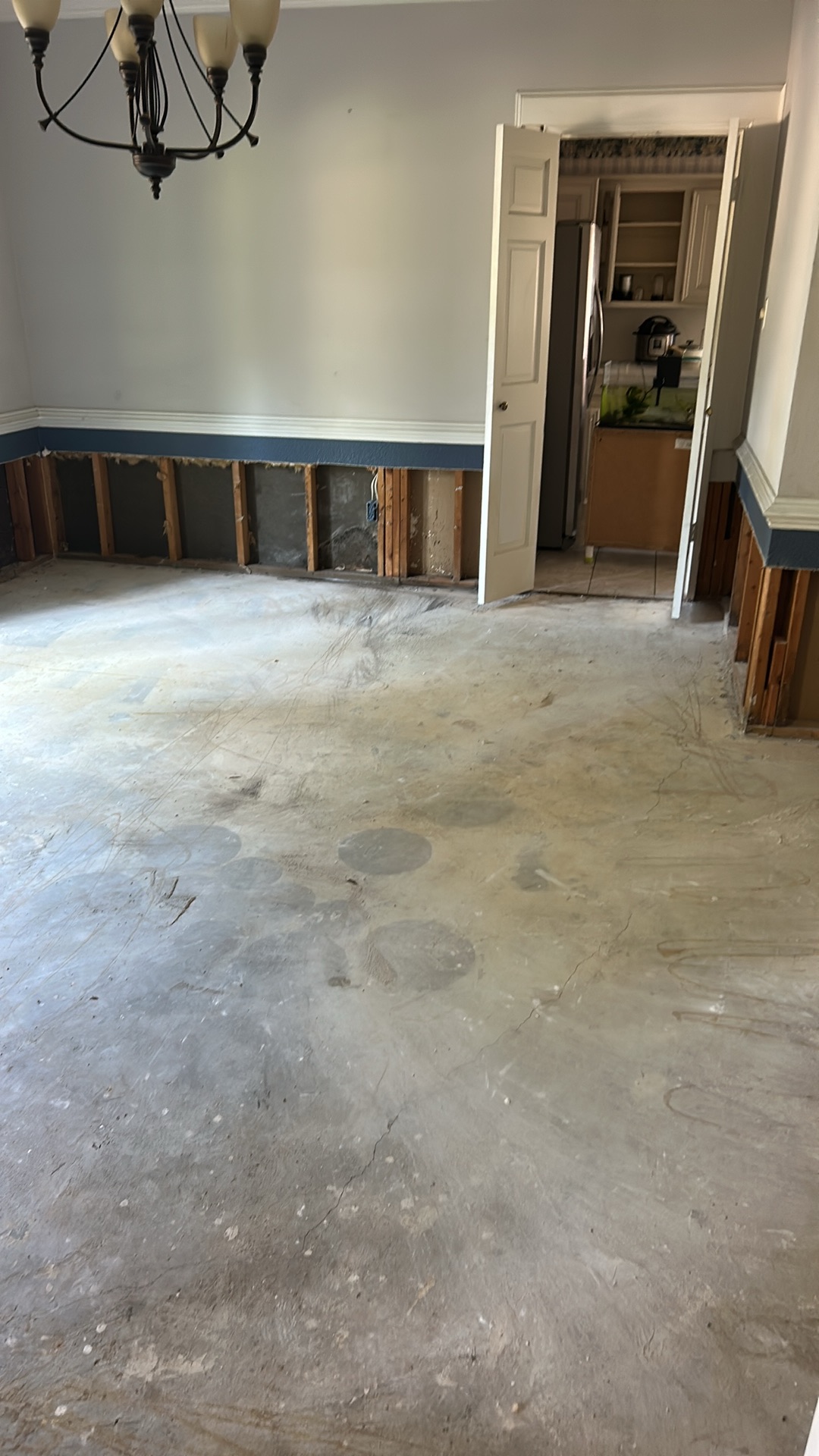 Room with lower walls demolished, exposing studs, indicating extensive fire and water damage restoration work.